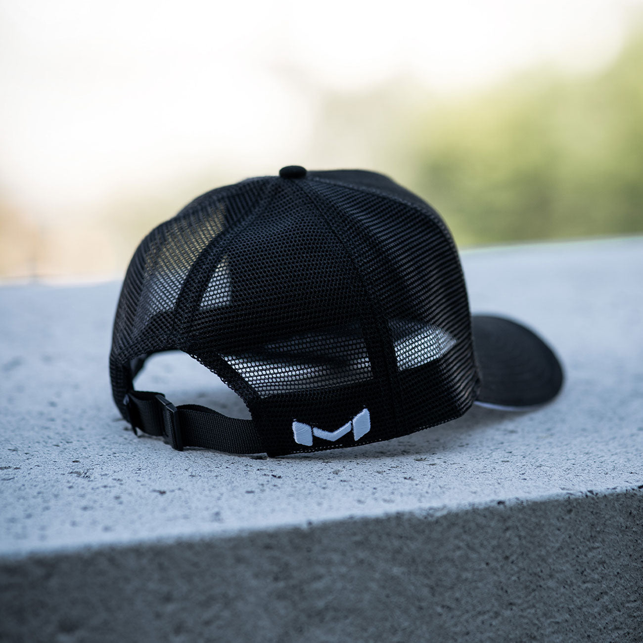 Back of the Moradness Air Flow mesh hat in black with adjustable clip closure and white embroidery