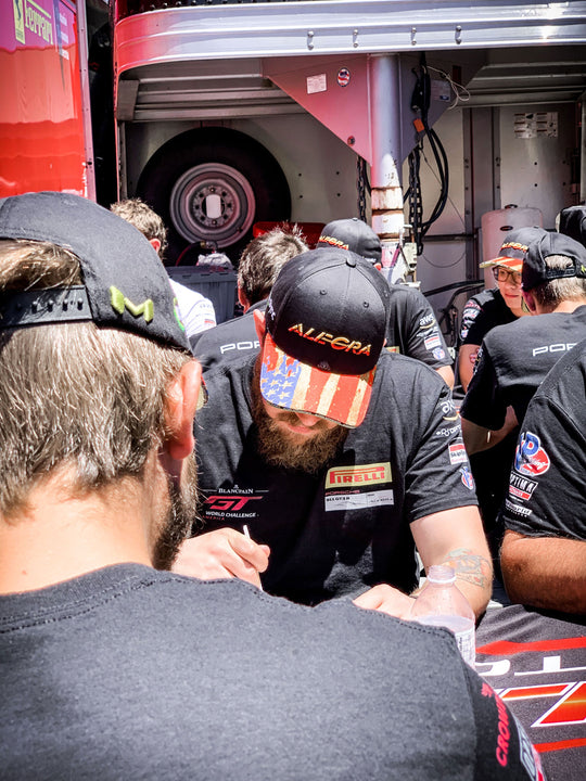 Alegra Motorsports crew member wearing the official team hat with american flag printed on the top of the brim